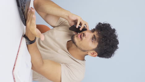 Video-Vertical-De-Un-Hombre-Usando-Una-Computadora-Portátil-Hablando-Nerviosamente-Por-Teléfono.
